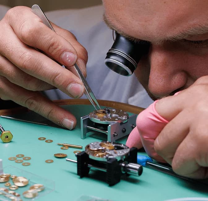 Watchmaker adjusting a movement under the loupe