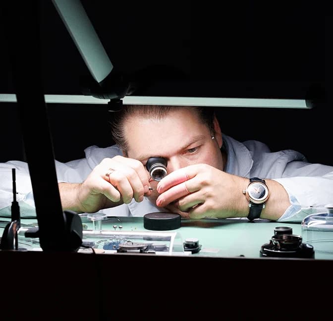 Watchmaker working with a loupe under the bench lamp