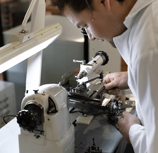 Watchmaker turning a part on a watchmaker's lathe